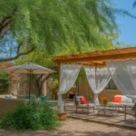 A cool and shady backyard oasis in Gilbert with a pergola, shade trees, and lush plants